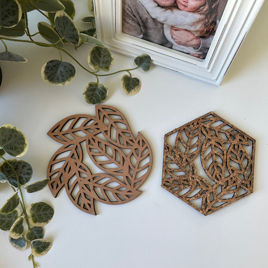 Two decorative trivets with a leave design and a photo frame in the background