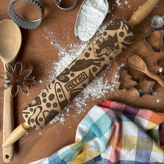 Baking tools including a rolling pin, wooden spoon, and cookie cutters on a wooden surface with flour.