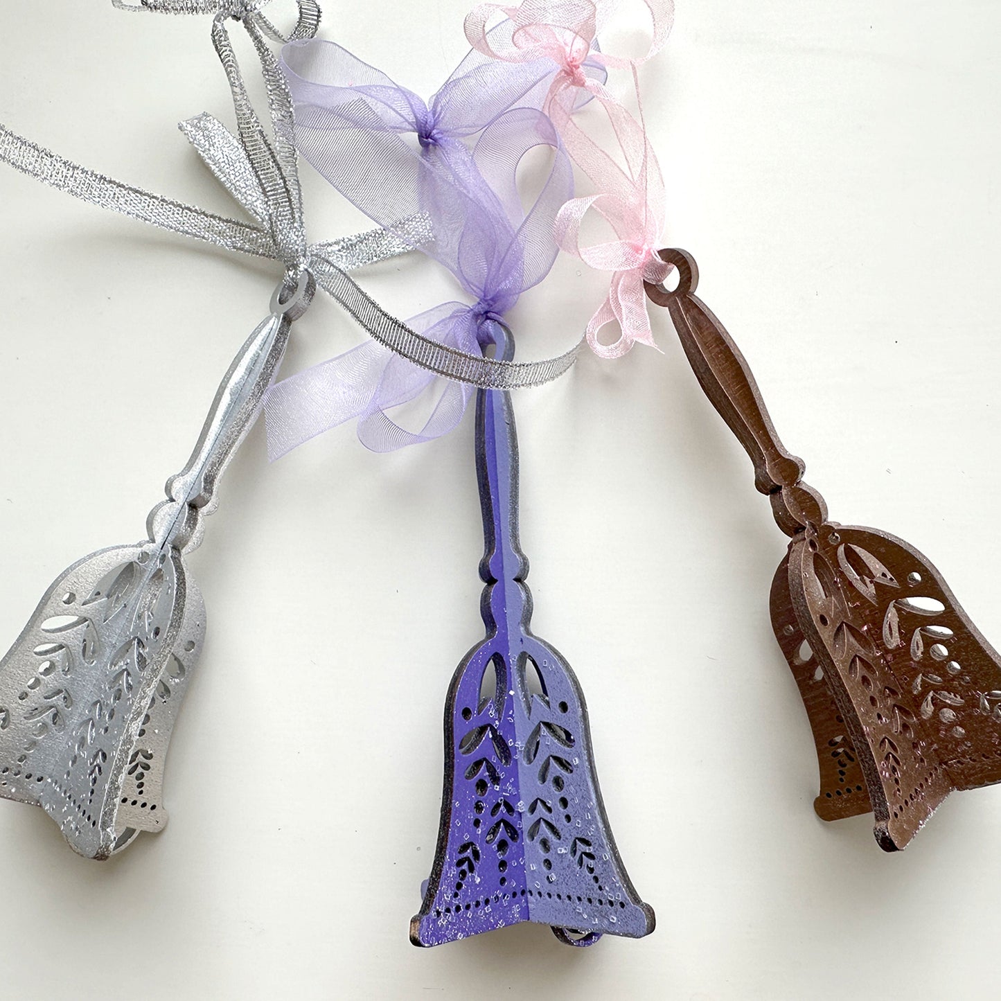 Three decorative bells with ribbons on a white background