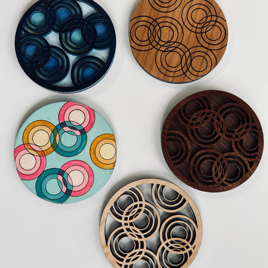 Five circular coasters with different designs on a white background