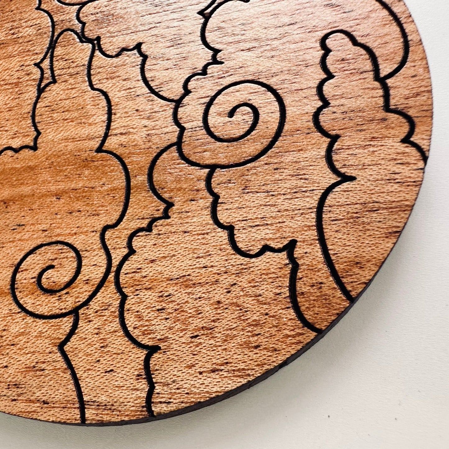 Wooden coaster with cloud patterns on a white background