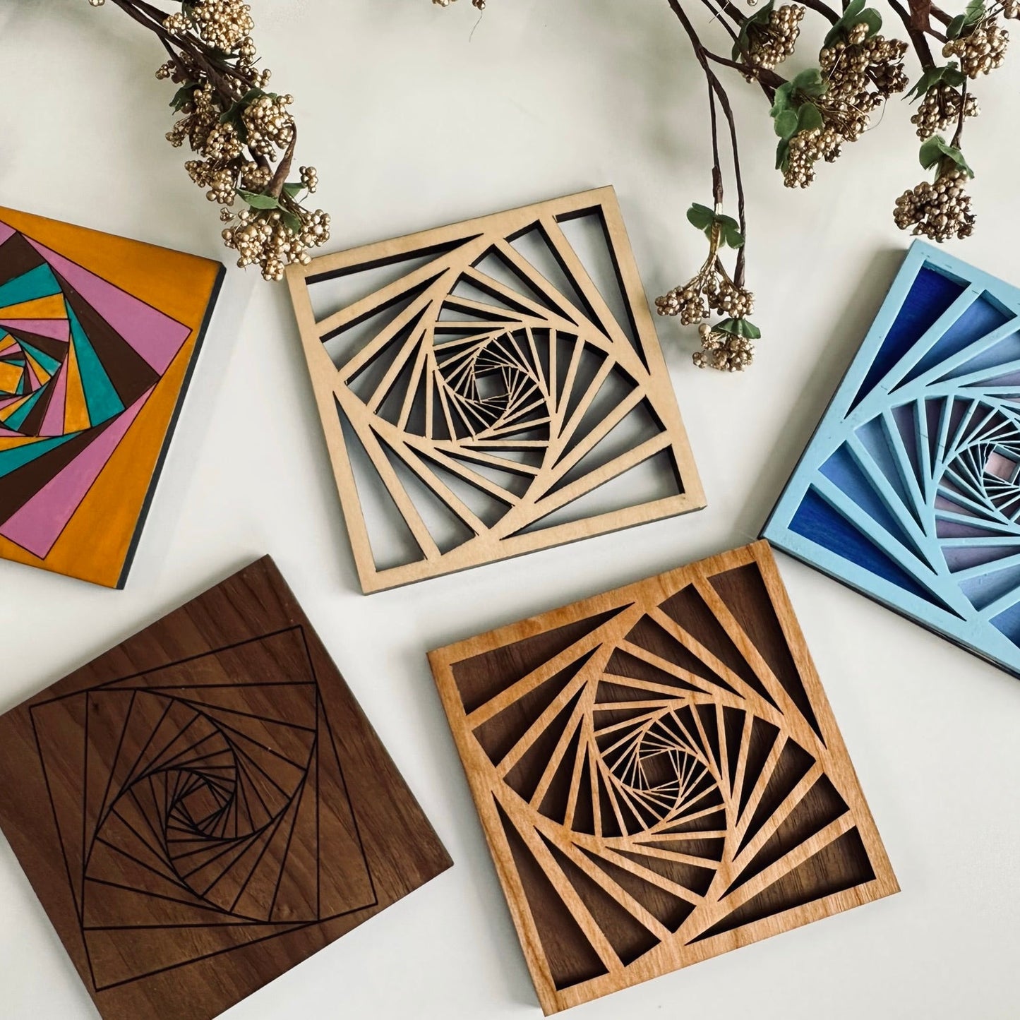 Five wooden coasters with geometric patterns on a white surface with decorative elements.