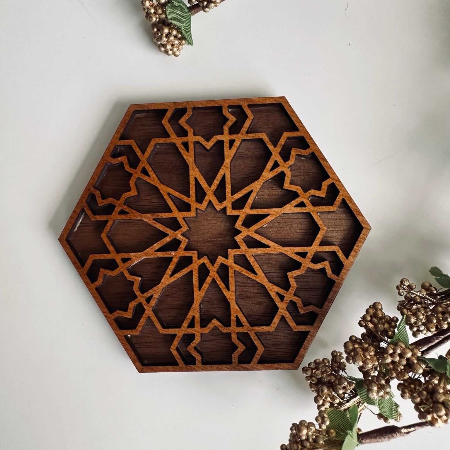 Hexagonal wooden decorative coaster with intricate patterns on a light background