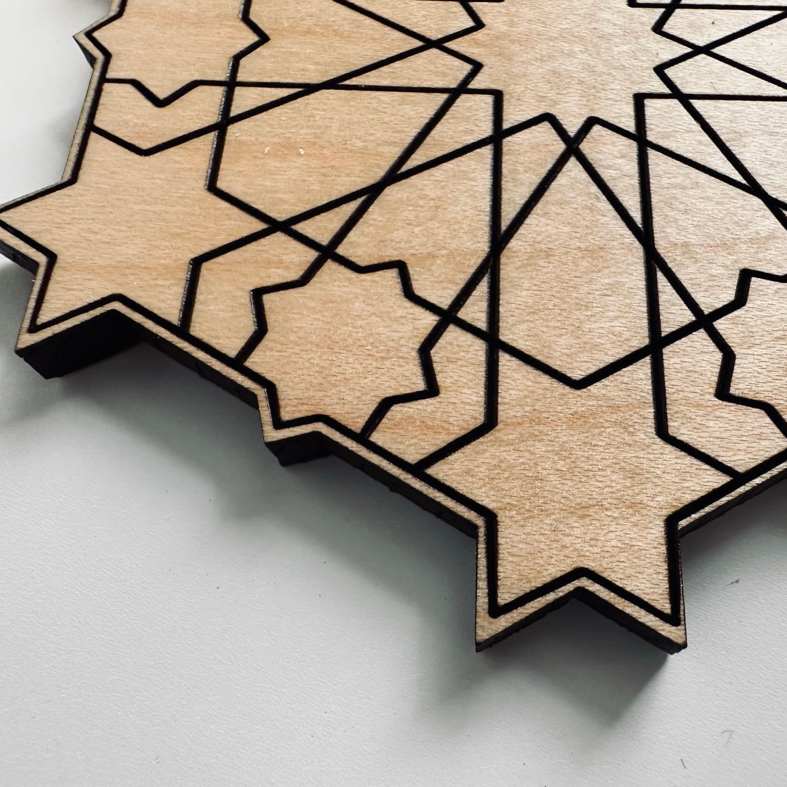 Wooden geometric star coaster on a light gray background