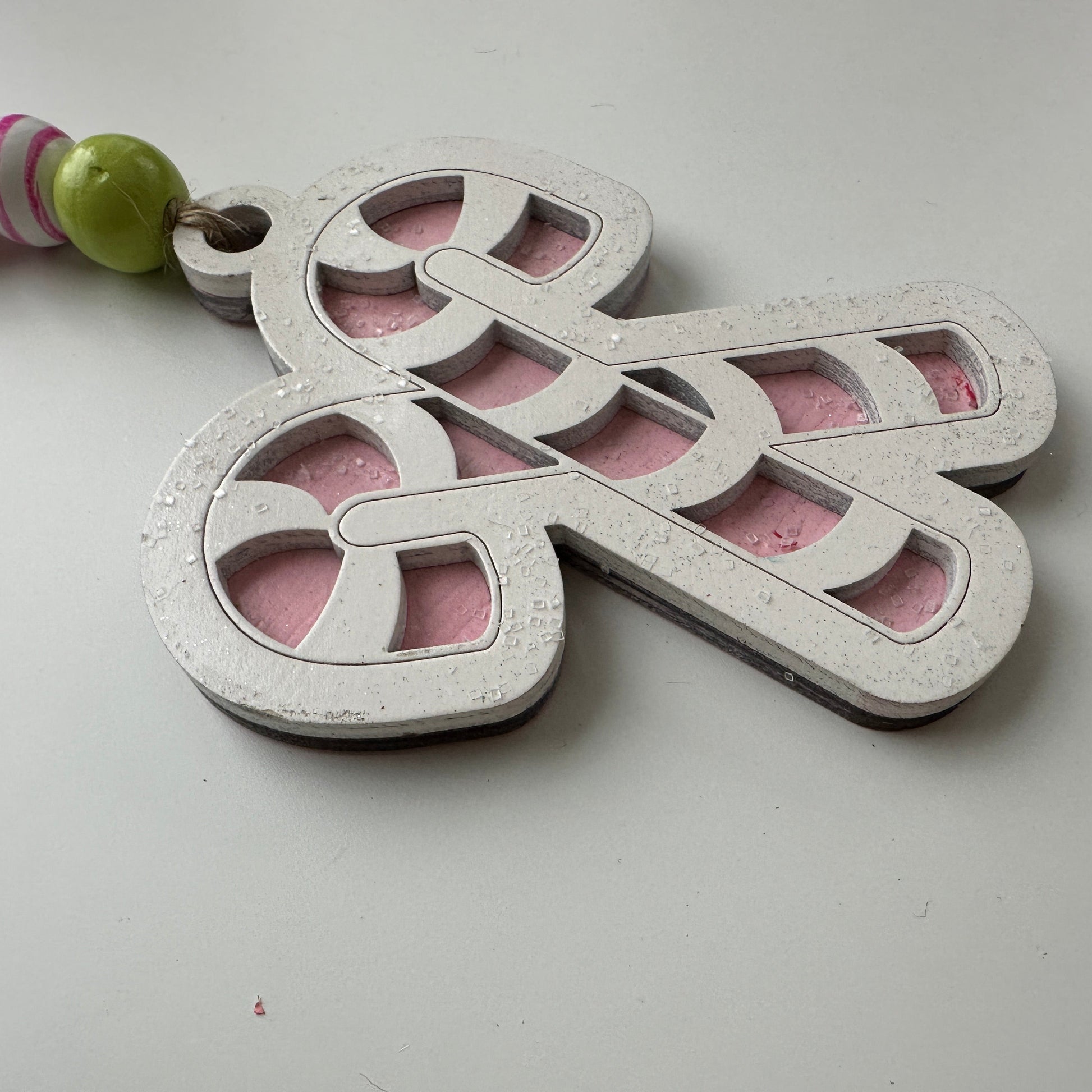 Christmas ornament with candy cane design and beads on a white background