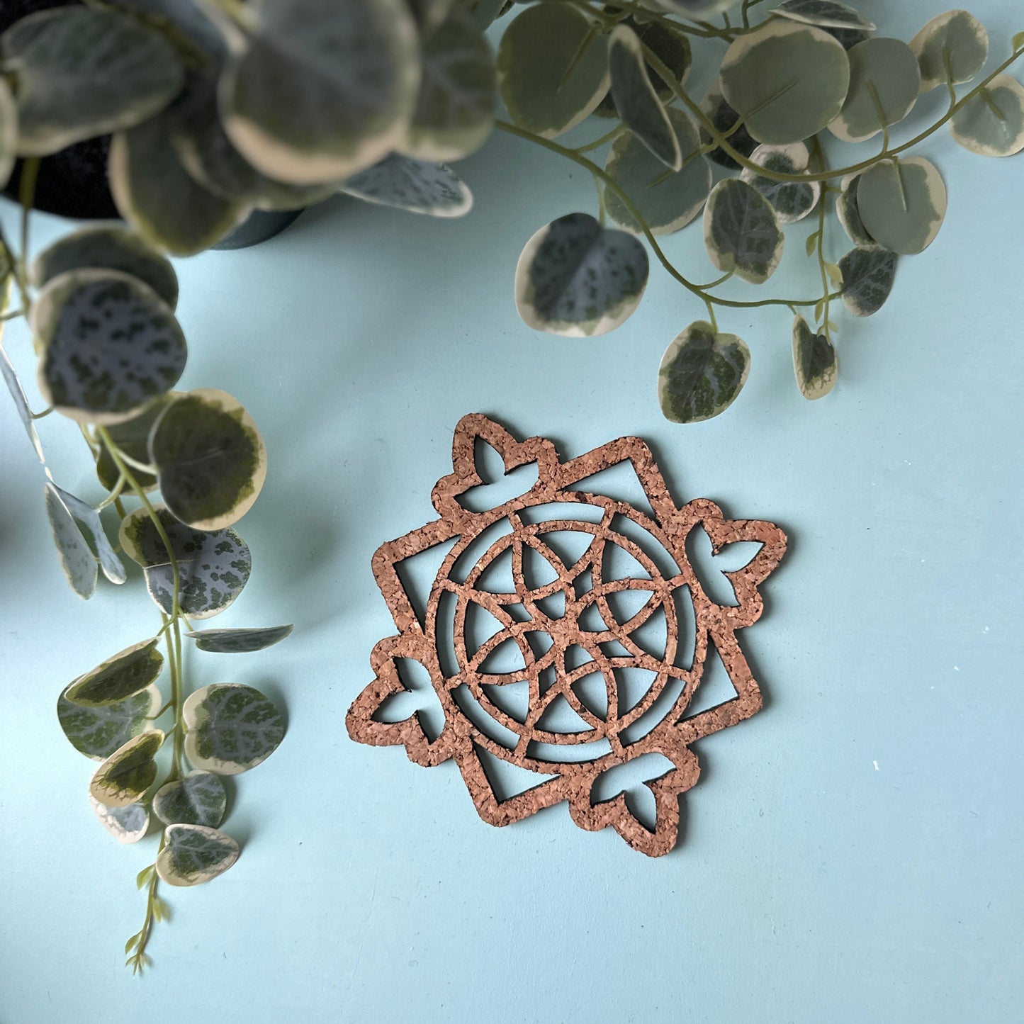 A cork trivet in a stained glass design on a blue background