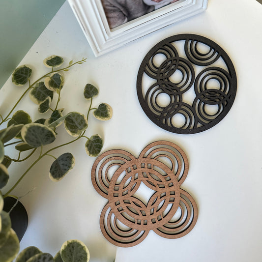 Decorative trivets on a white surface with a framed photo and plant.