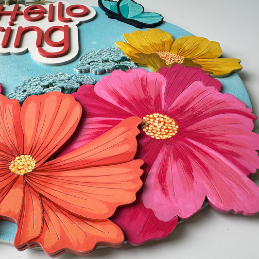 Colorful paper flowers with 'Hello Spring' text on a blue background