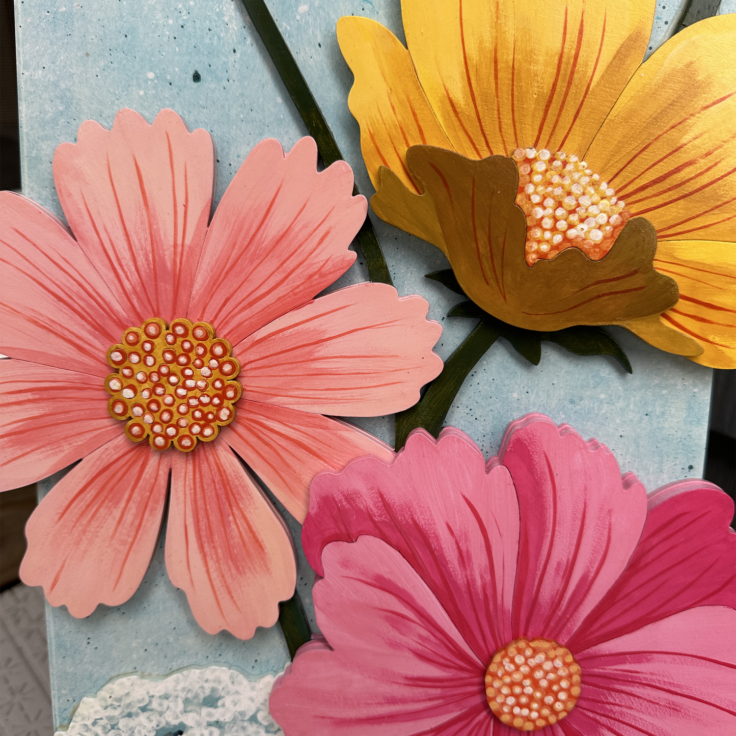 Close-up of colorful wooden flowers on a textured surface