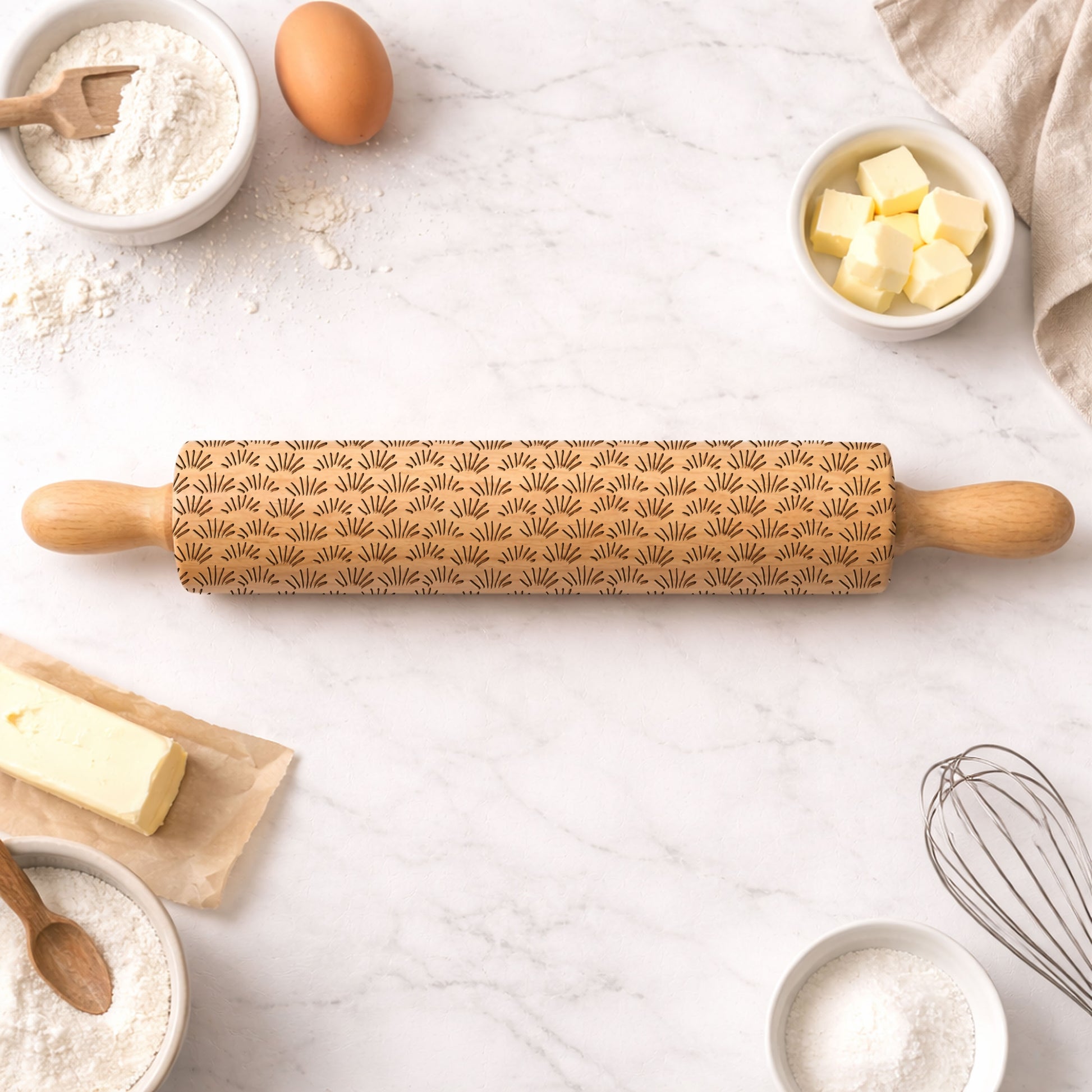 Decorative rolling pin with embossed patterns on a kitchen counter with baking ingredients.