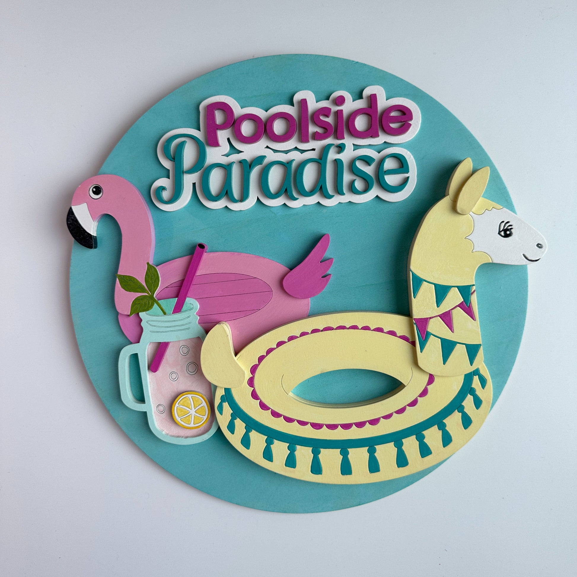 Decorative sign with 'Poolside Paradise' text, flamingo, drink, and pool float on a teal background.