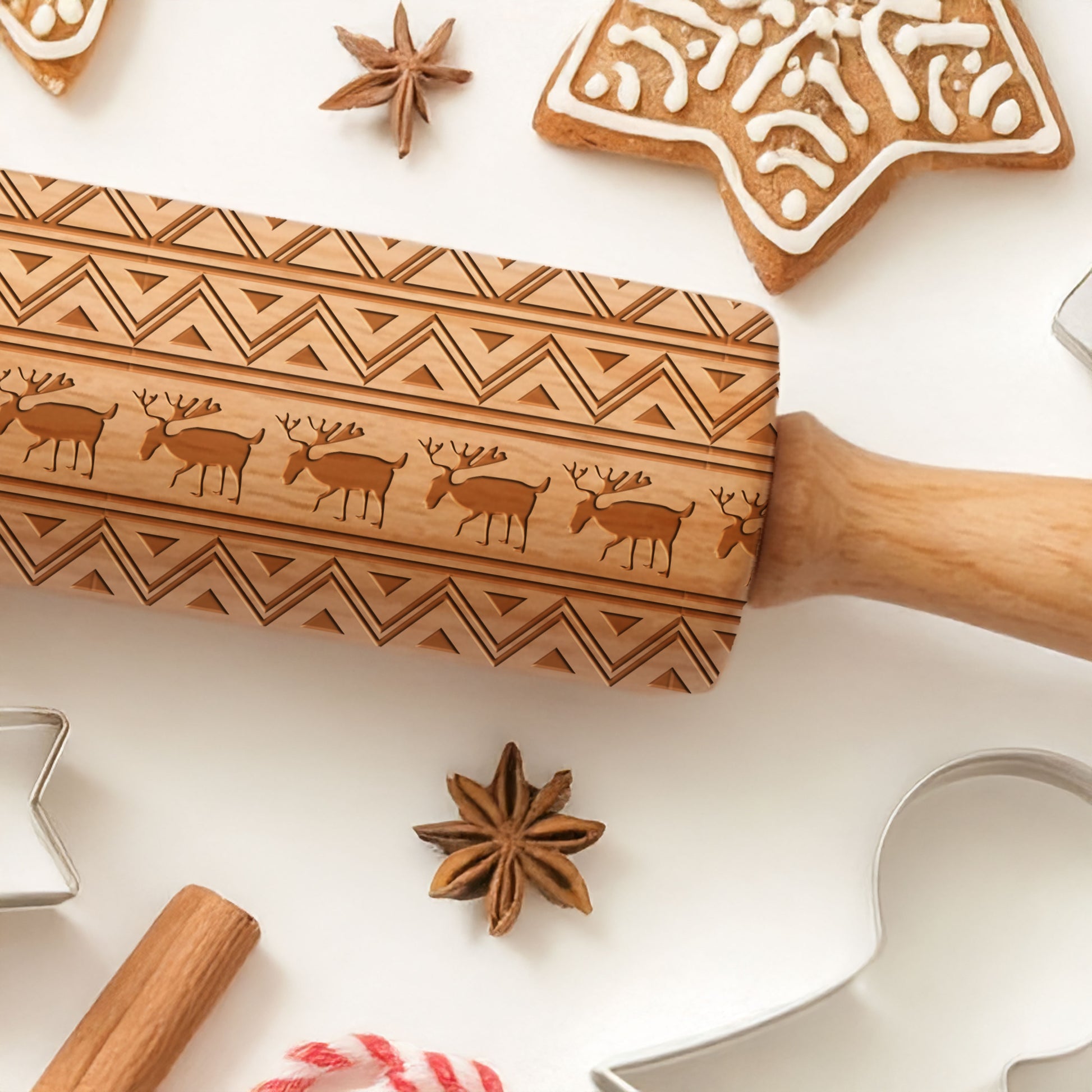 Wooden embossing rolling pin with cookie cutters and spices on a white surface