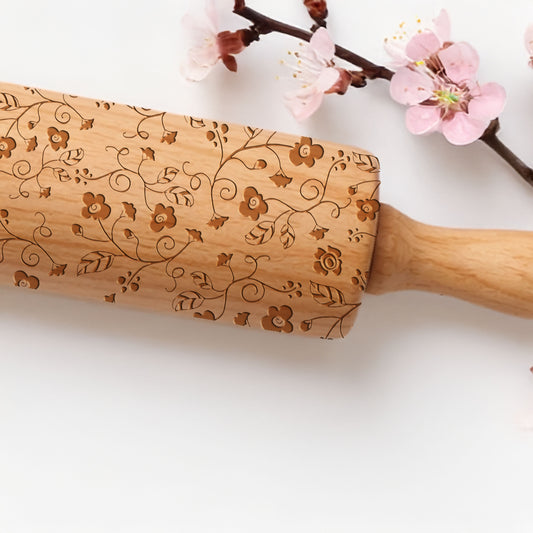 Wooden rolling pin with floral patterns on a white background with cherry blossoms.