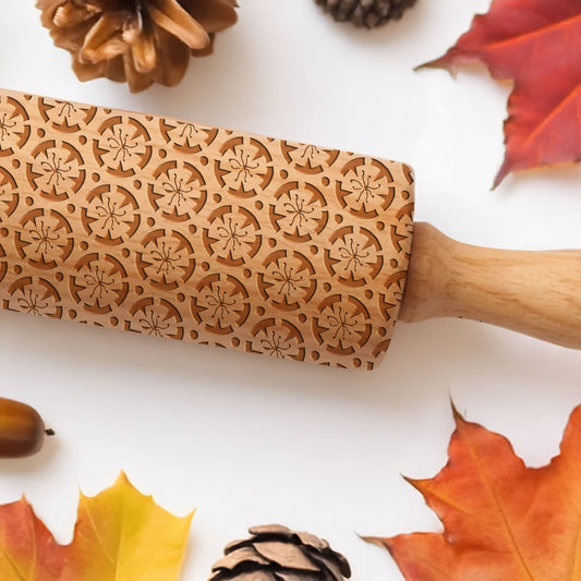 Wooden rolling pin with autumn-themed patterns on a white background with leaves and pinecones.
