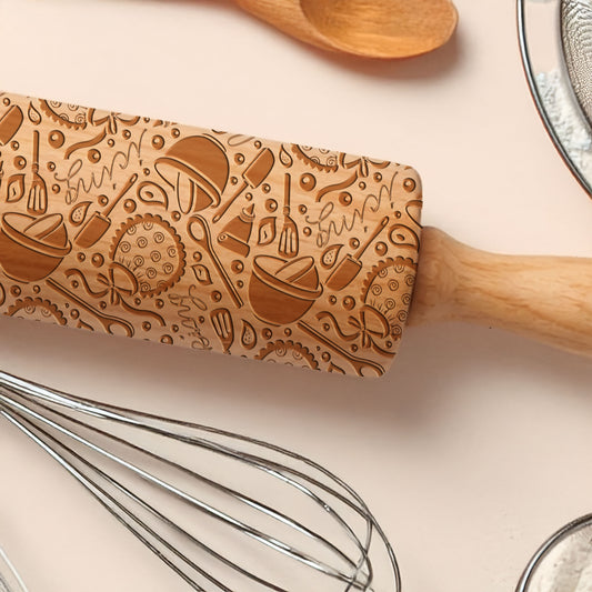 Wooden rolling pin with engraved designs on a kitchen counter with utensils.