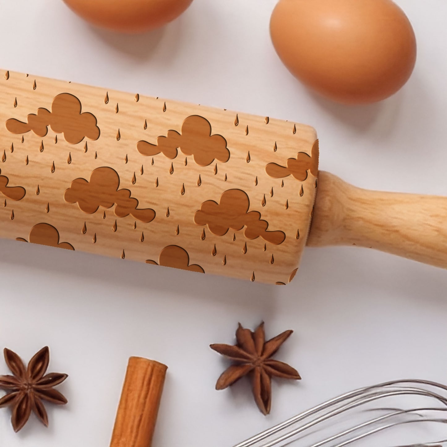 Wooden rolling pin with star anise, cinnamon stick, and whisk on a white background