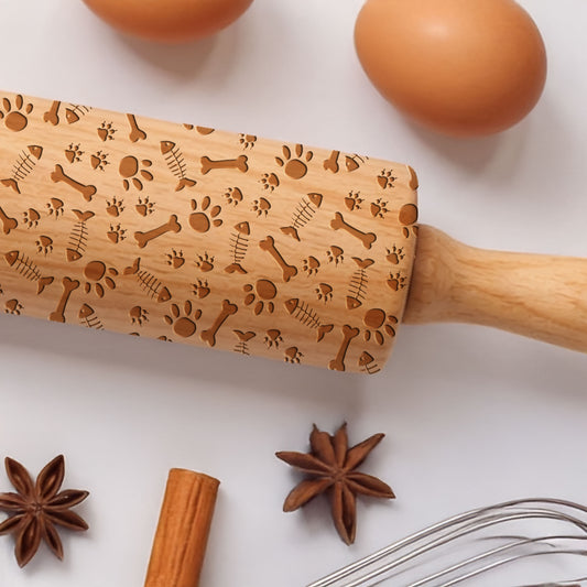 Wooden rolling pin with engraved patterns on a white surface with eggs, star anise, cinnamon stick, and whisk.