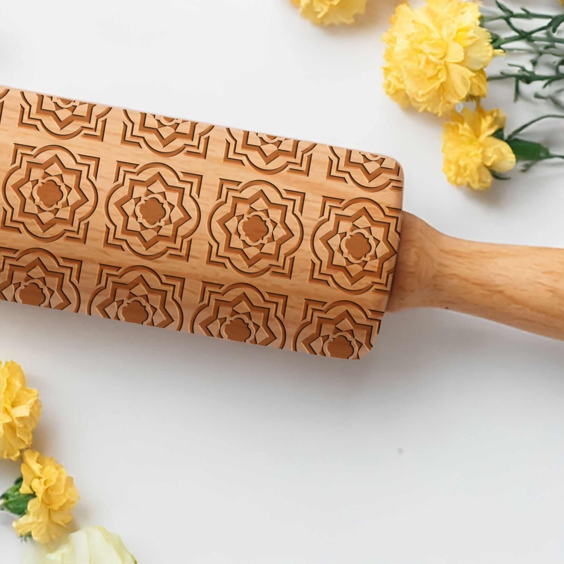 Wooden rolling pin with decorative patterns on a white background with yellow flowers.