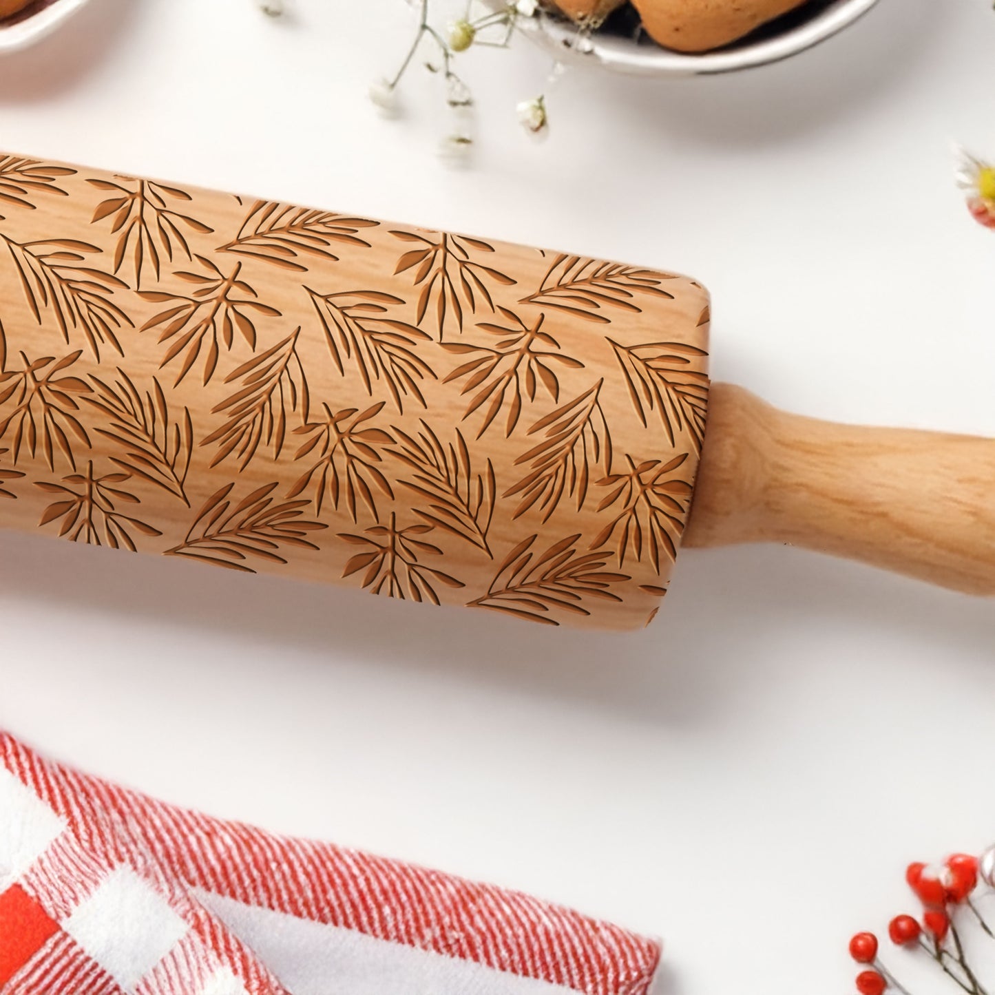 Wooden rolling pin with leaf pattern on a white surface