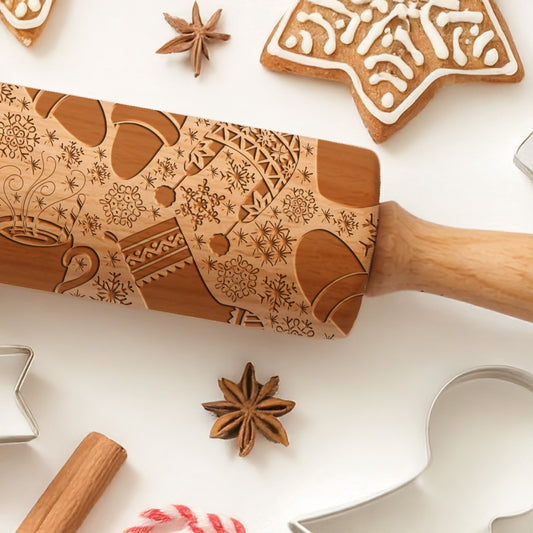 Wooden embossing rolling pin with decorative patterns on a white surface with cookies and spices.