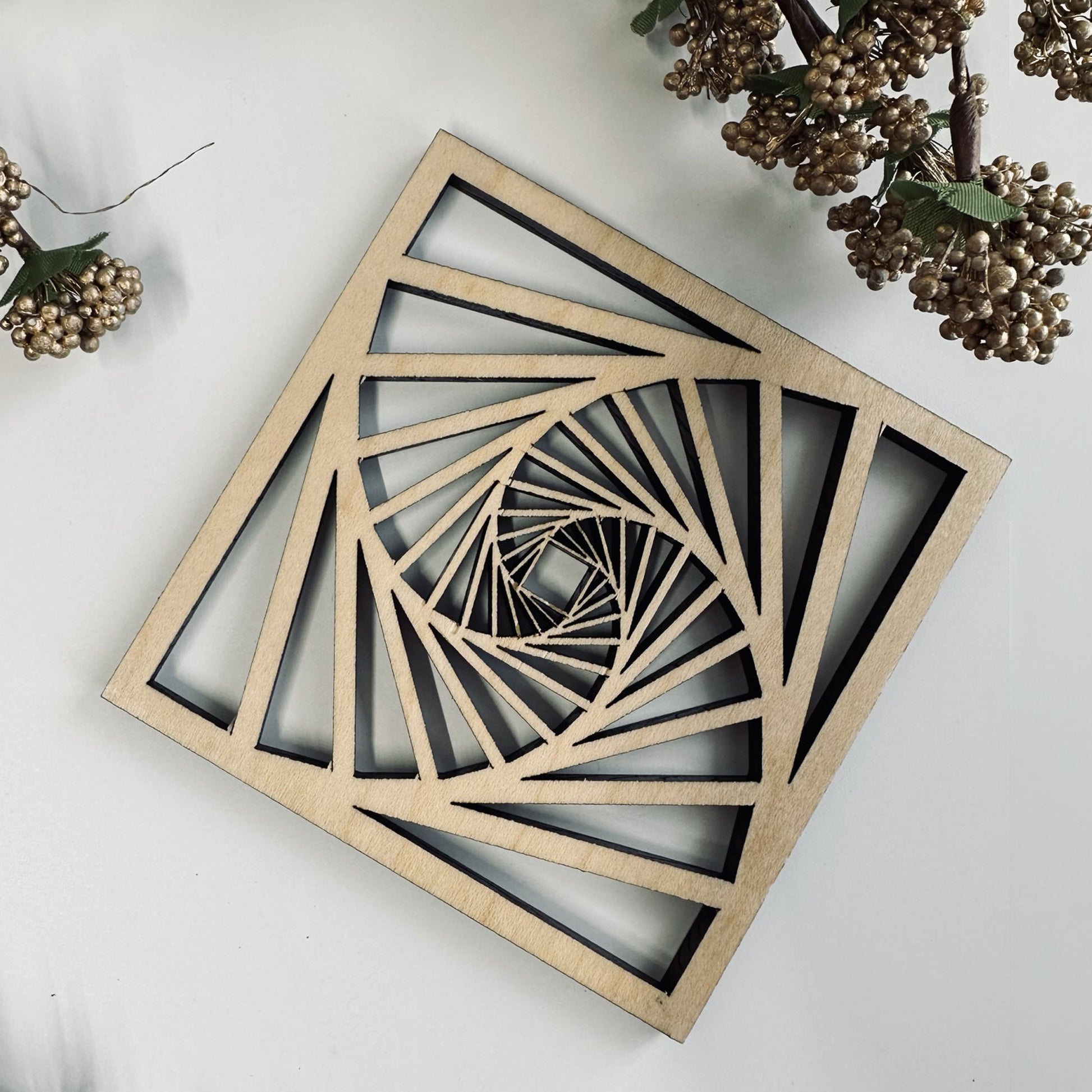 Geometric wooden coaster with a spiral design on a white surface.