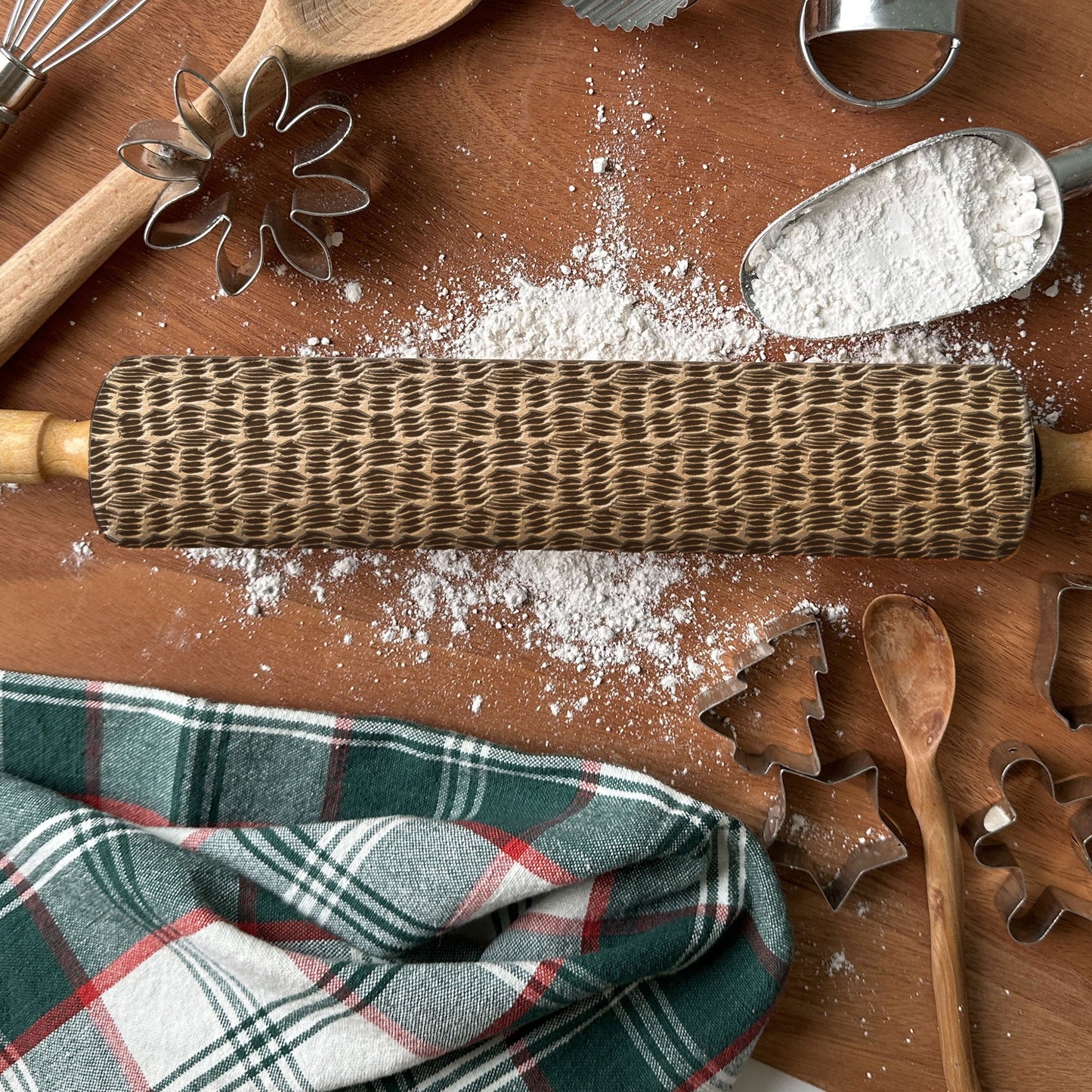 Wooden rolling pin with flour and baking tools on a wooden surface