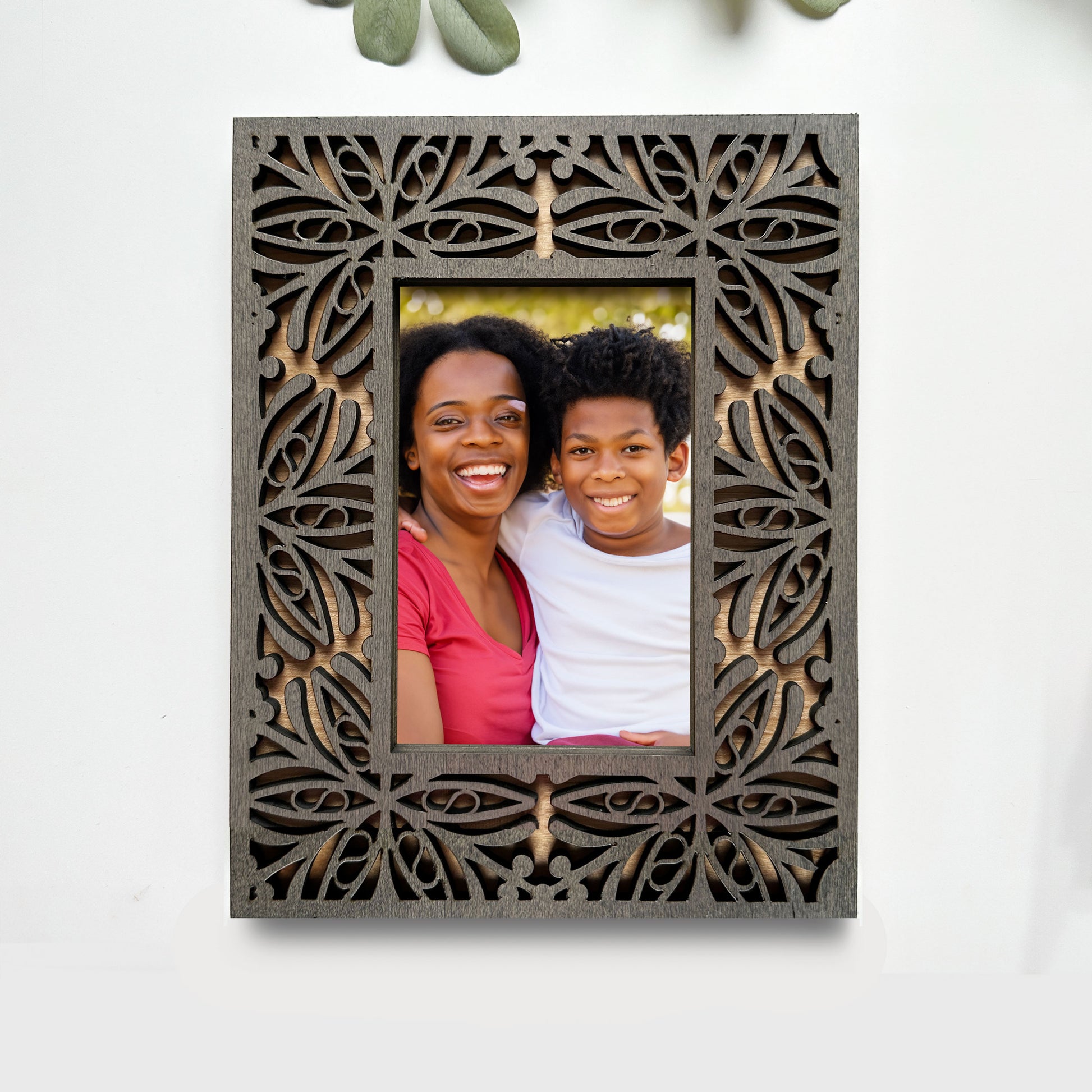 Decorative photo frame with cut-out patterns holding a photo of two people.