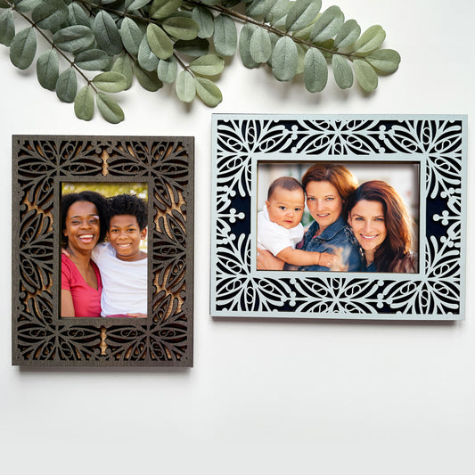Two decorative picture frames with family photos on a white background with green leaves.
