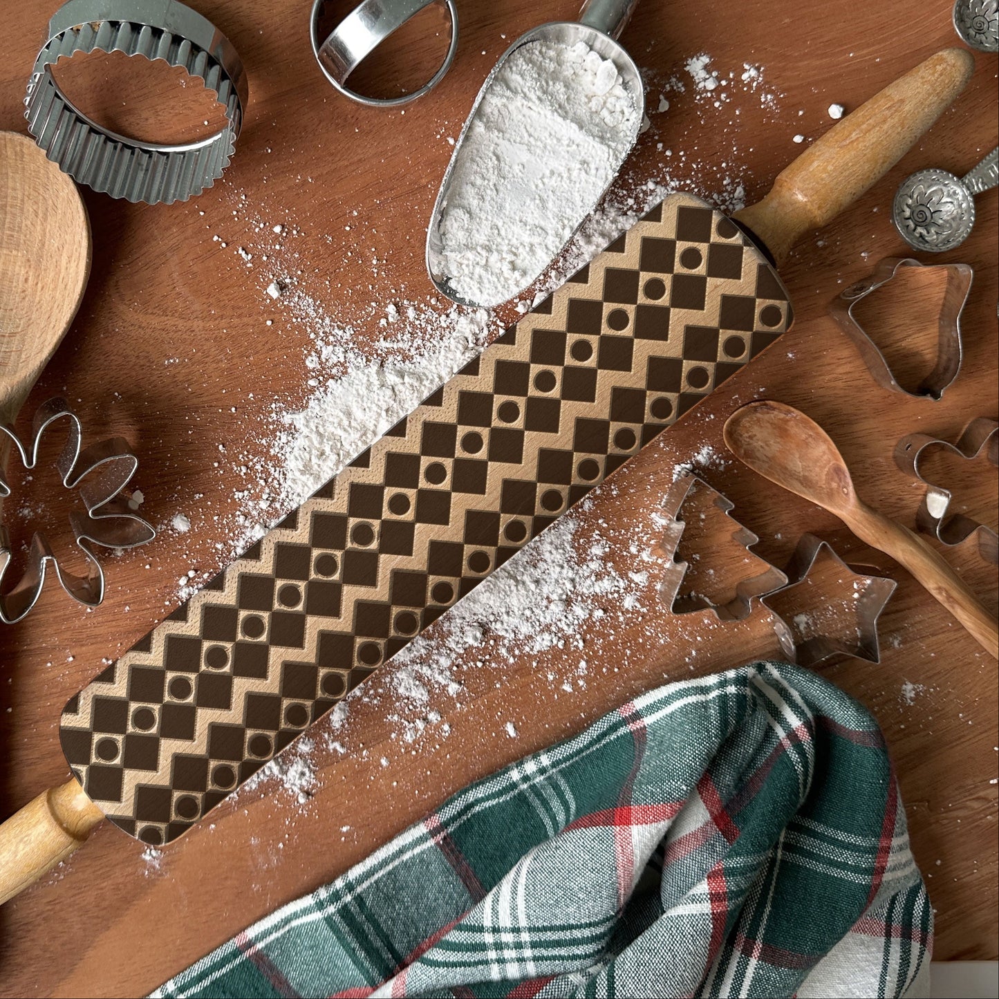 Wooden kitchen utensils including a rolling pin, spatula, and cookie cutters on a wooden surface with flour.