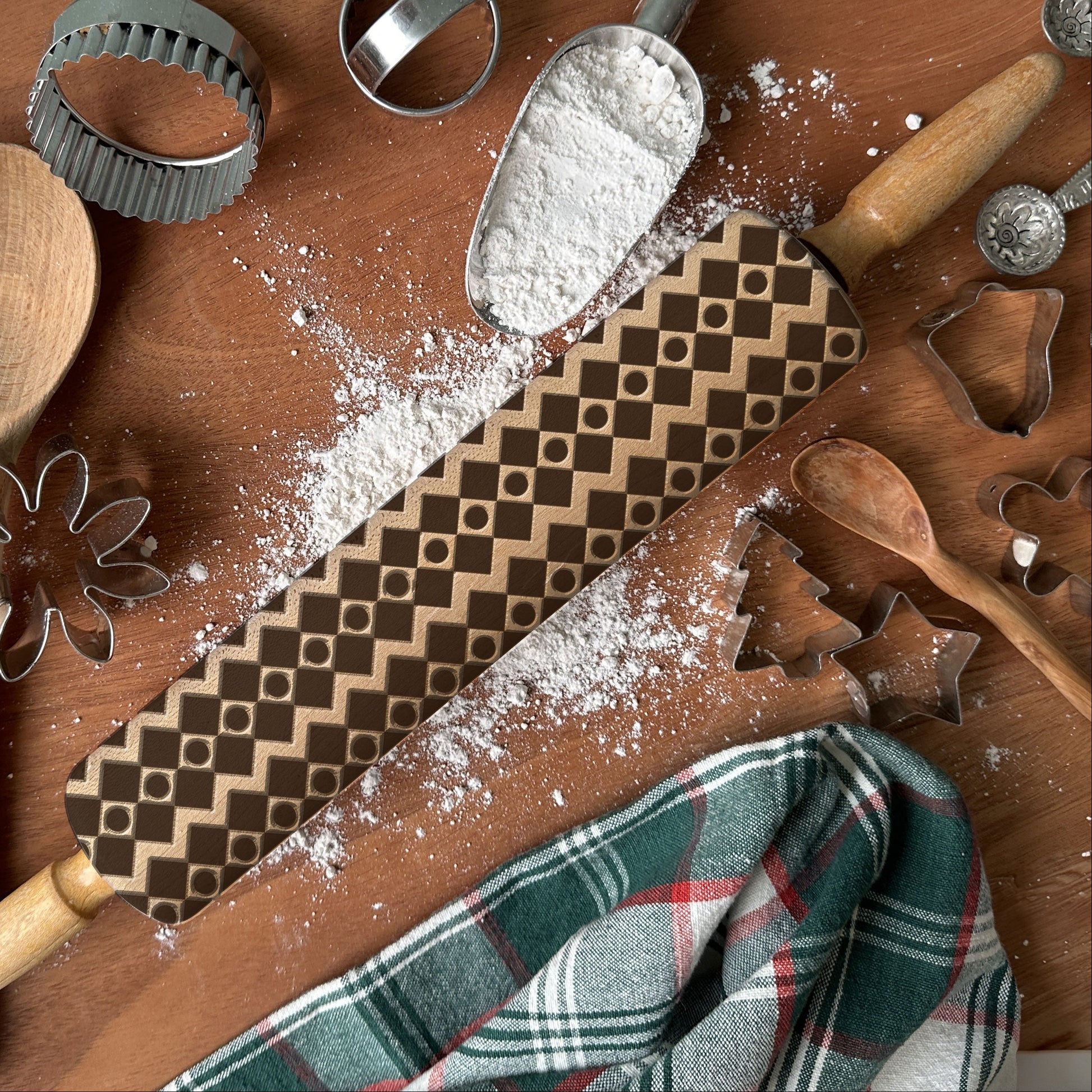 Wooden kitchen utensils including a rolling pin, spatula, and cookie cutters on a wooden surface with flour.