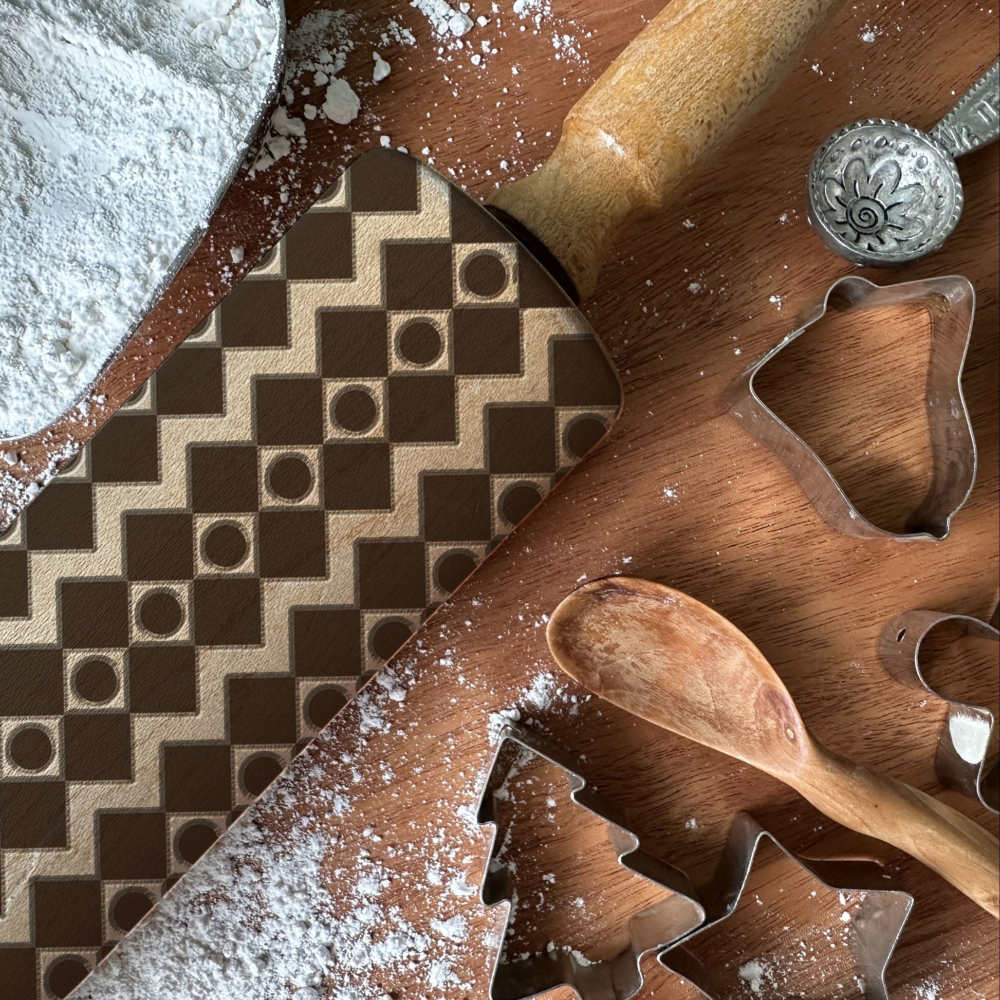 Wooden cutting board with cookie cutters, flour, and a patterned surface.