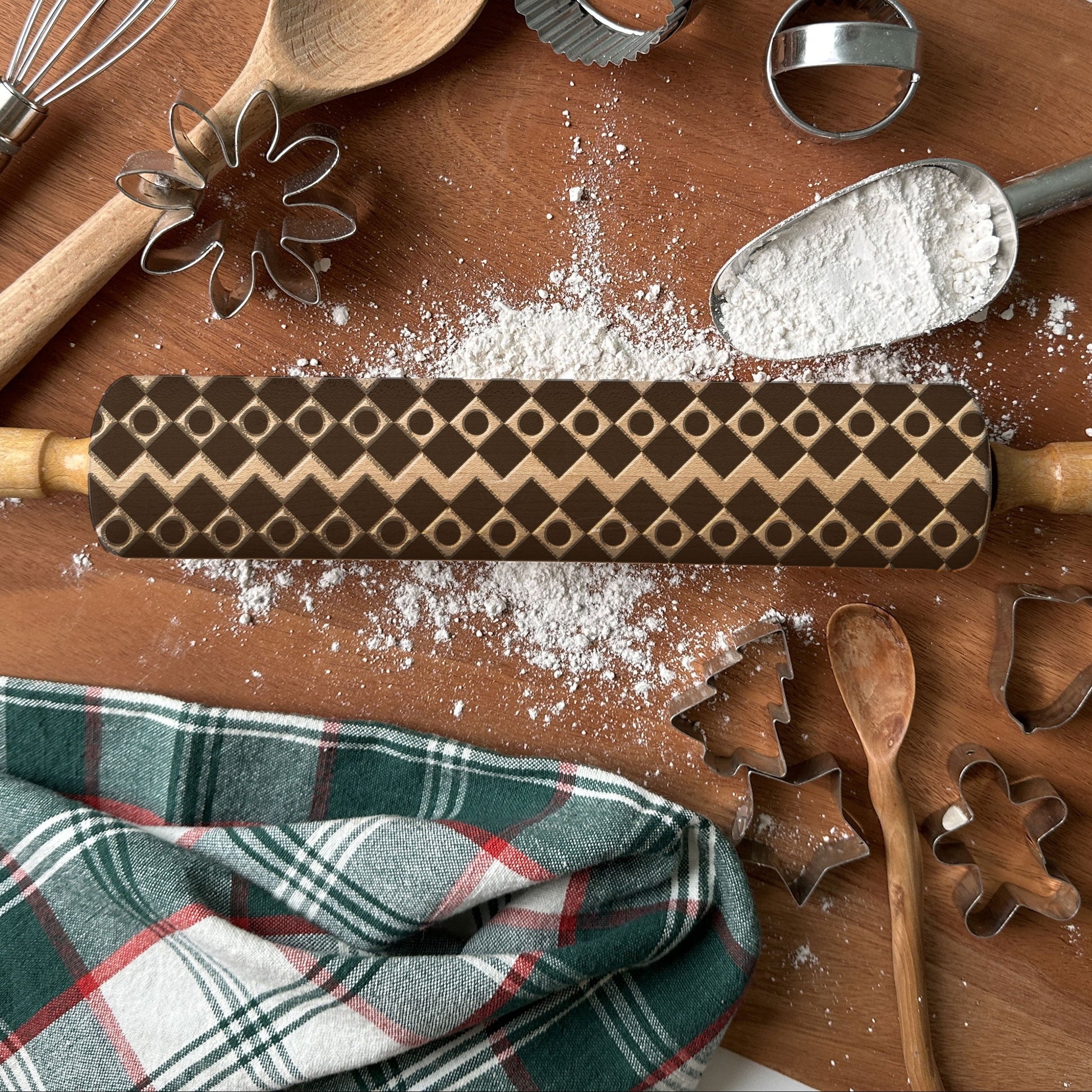 Baking tools including a rolling pin, wooden spoon, and cookie cutters on a wooden surface with flour.