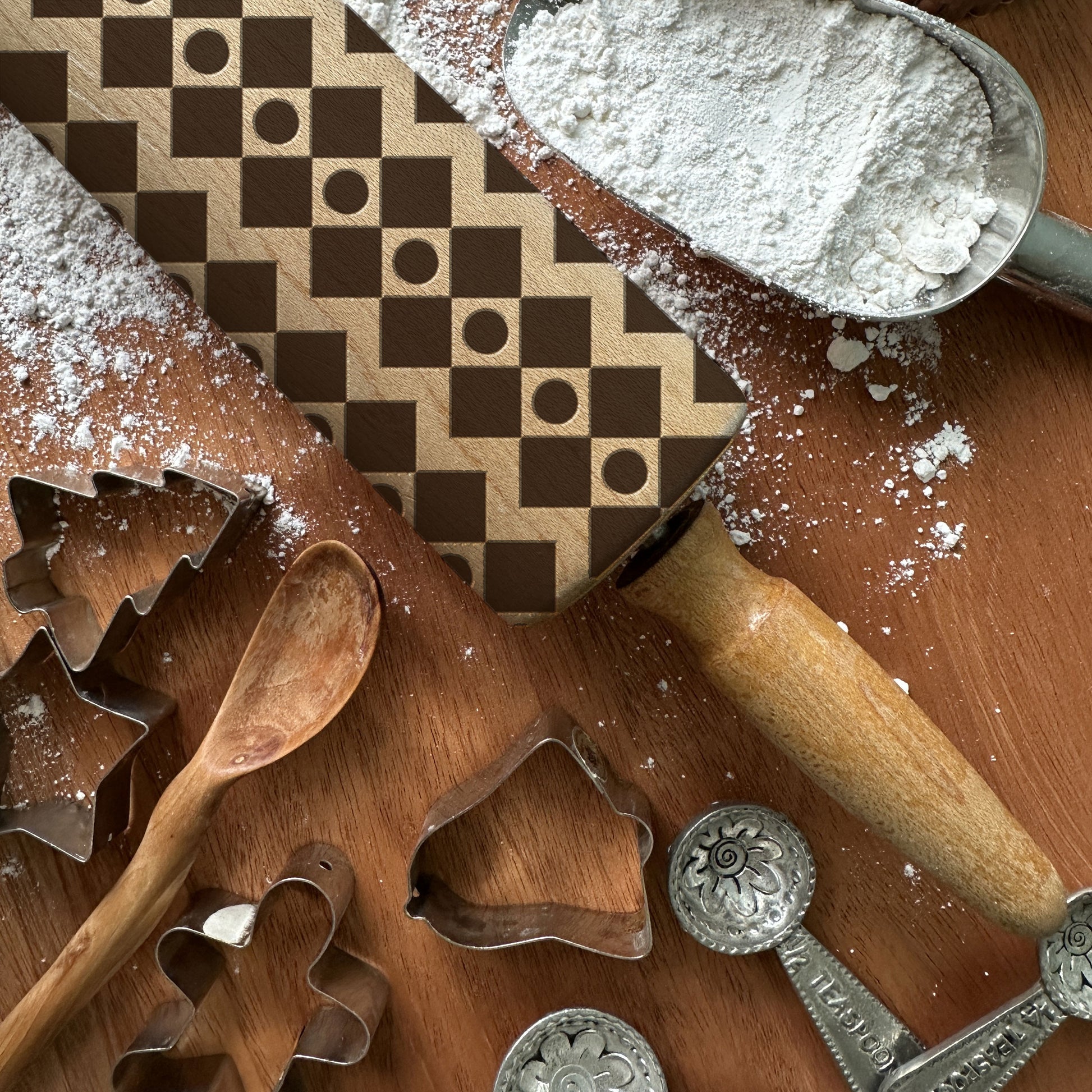 Baking tools including cookie cutters and a rolling pin on a wooden surface with flour.