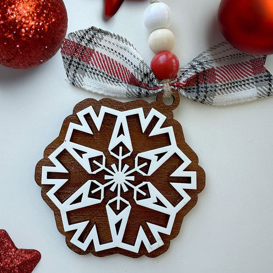 Wooden snowflake ornament with decorative ribbon and beads on a white background