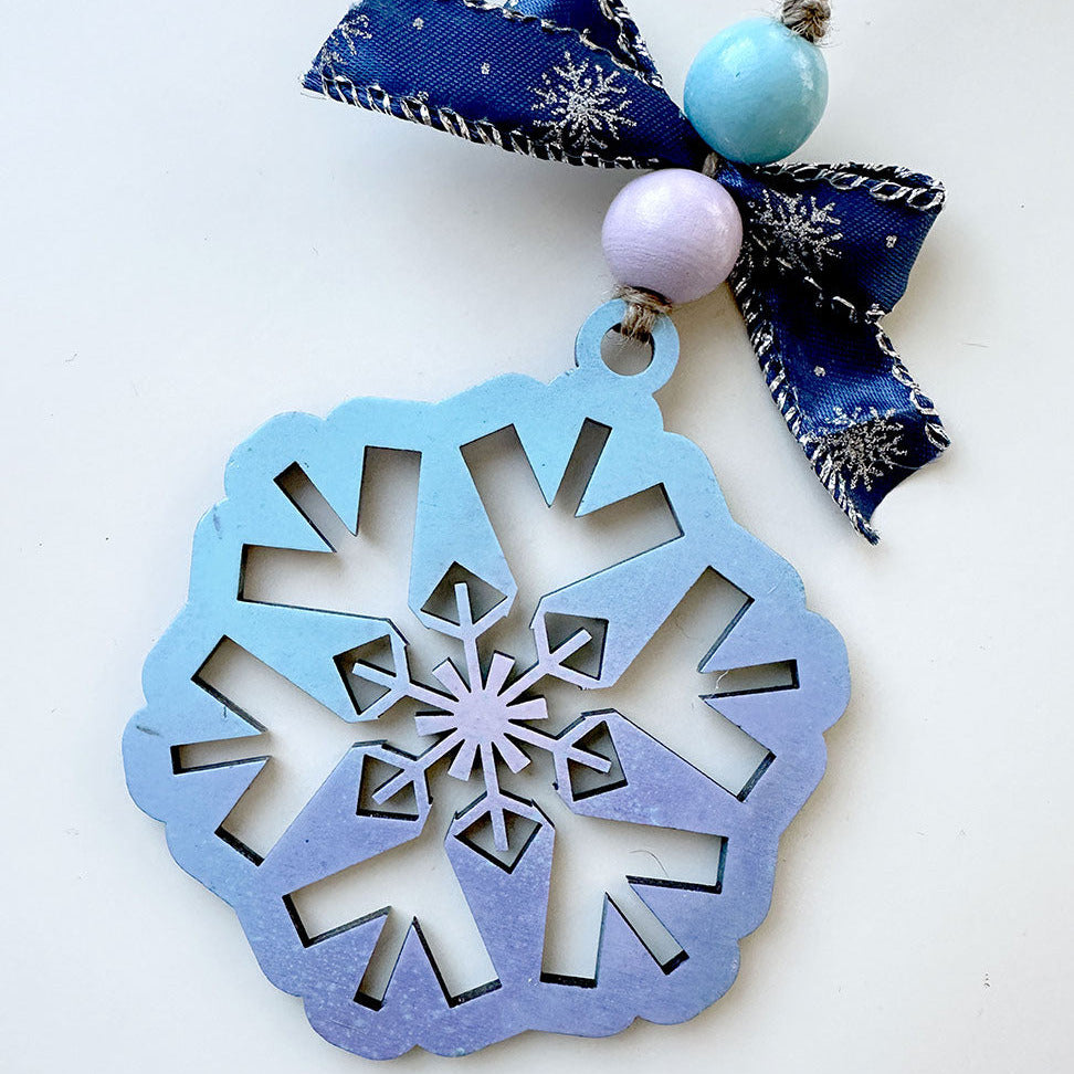 Decorative snowflake ornament with blue ribbon and beads on a white background