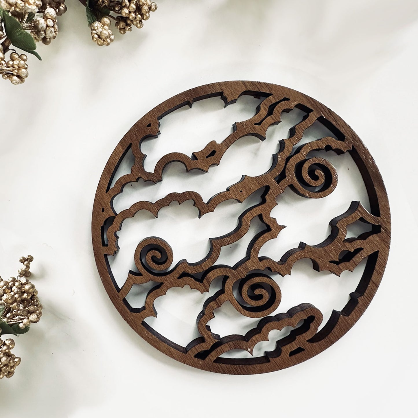 Decorative wooden coaster with intricate cut-out patterns on a white background