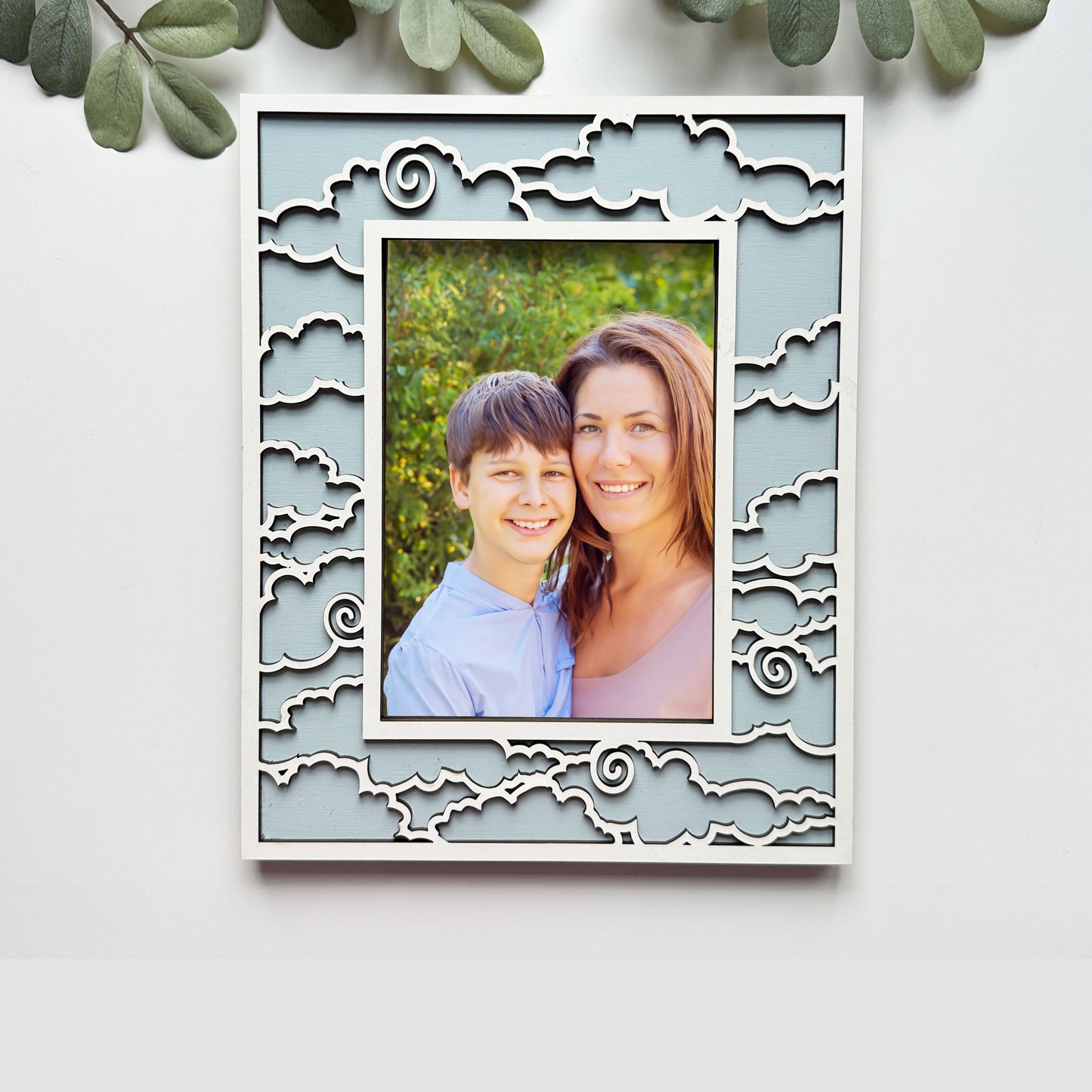 Decorative photo frame with a cut-out design, containing a photo of a smiling couple, on a light background.