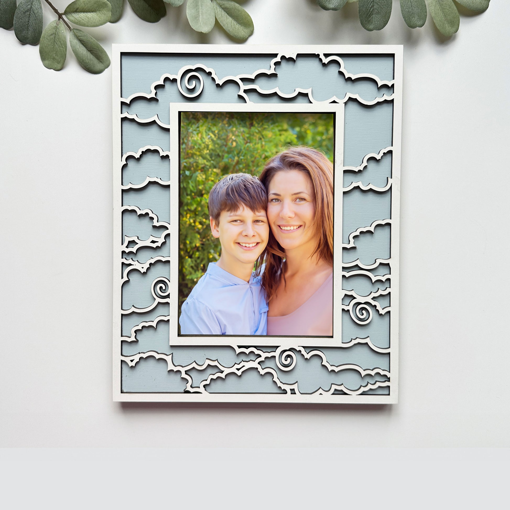 Decorative photo frame with a cut-out design, containing a photo of a smiling couple, on a light background.