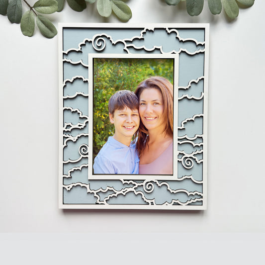 Decorative photo frame with a cut-out design, containing a photo of a smiling couple, on a light background.