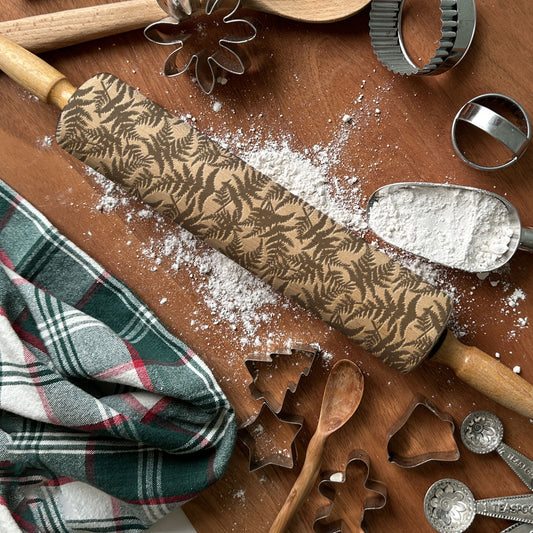 Wooden rolling pin with engraved patterns on a wooden surface with baking tools.