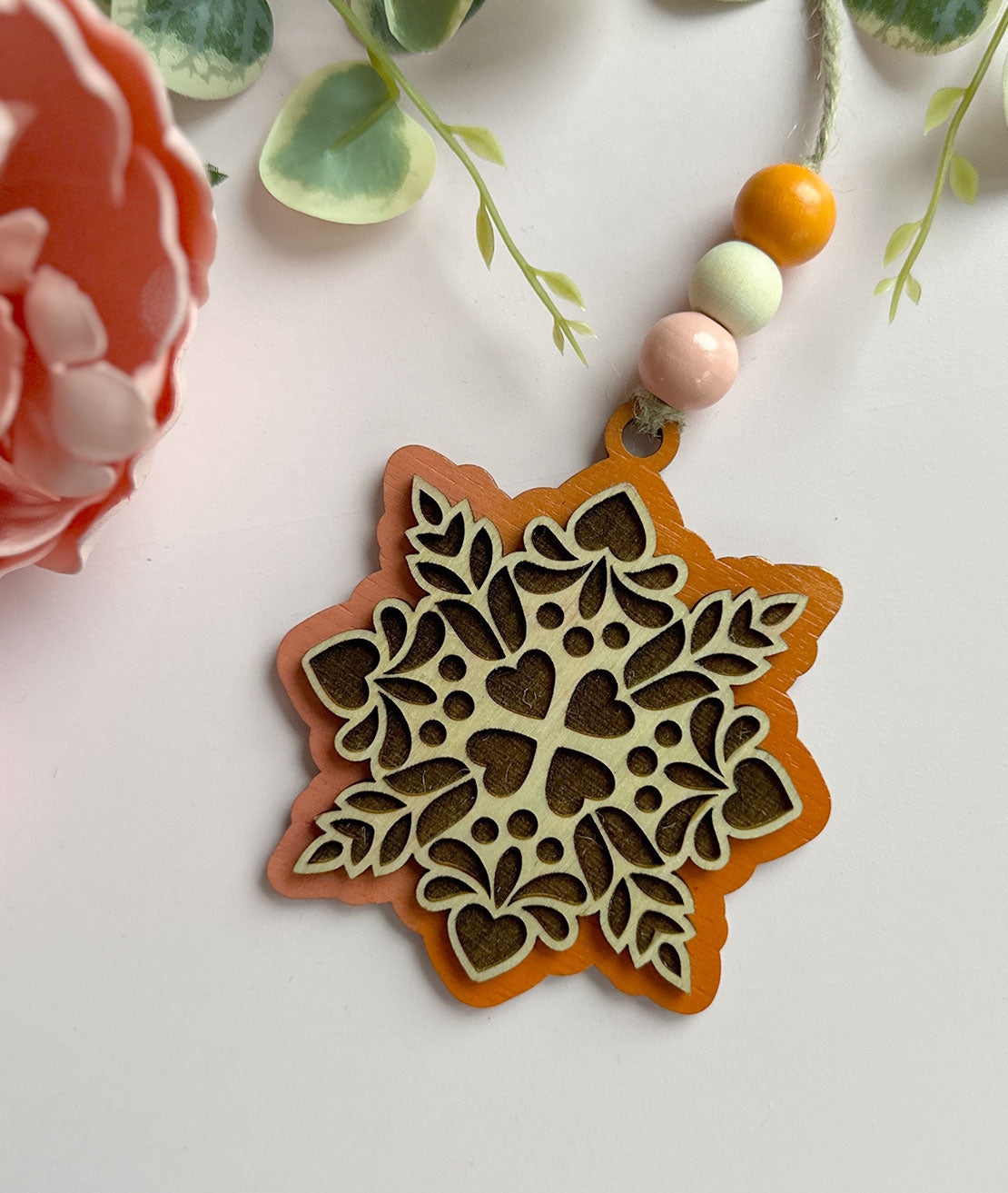 Decorative wooden ornament with floral pattern on a light background
