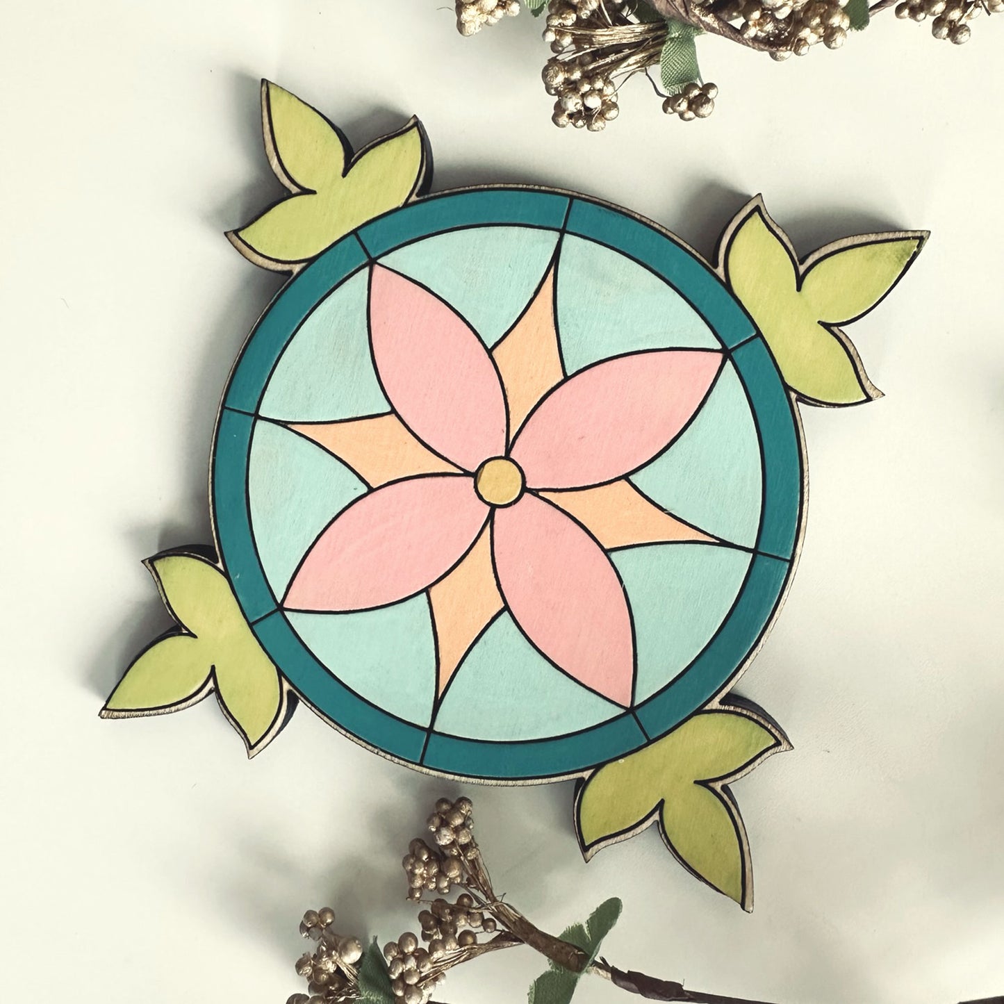Decorative coaster with a pink flower and green leaves on a white background