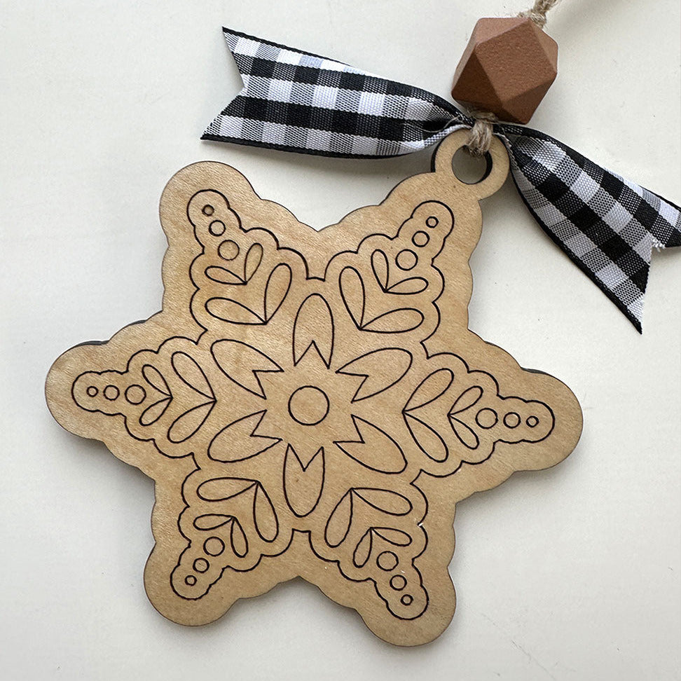 Wooden snowflake ornament with a checkered ribbon on a white background