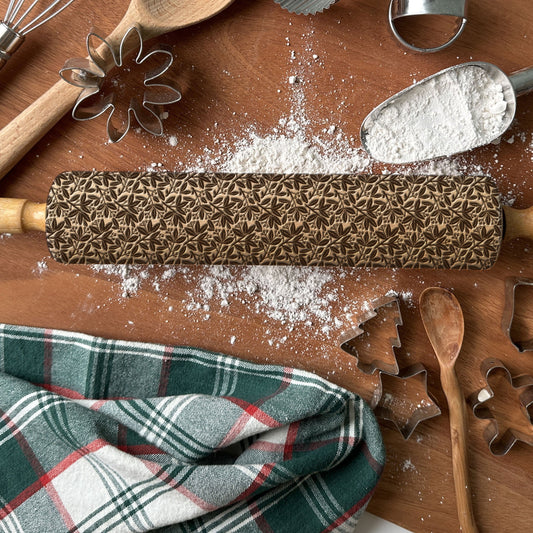 Patterned rolling pin with baking tools on a wooden surface with flour.