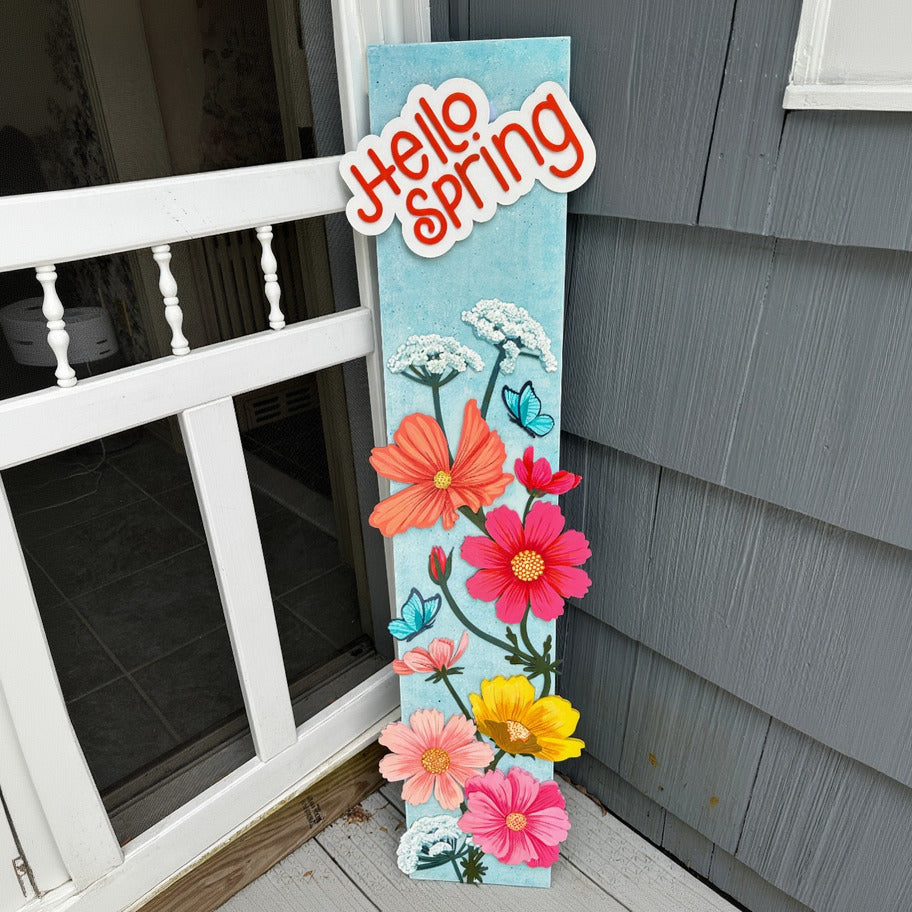 Decorative sign with flowers and 'Hello Spring' text on a porch.