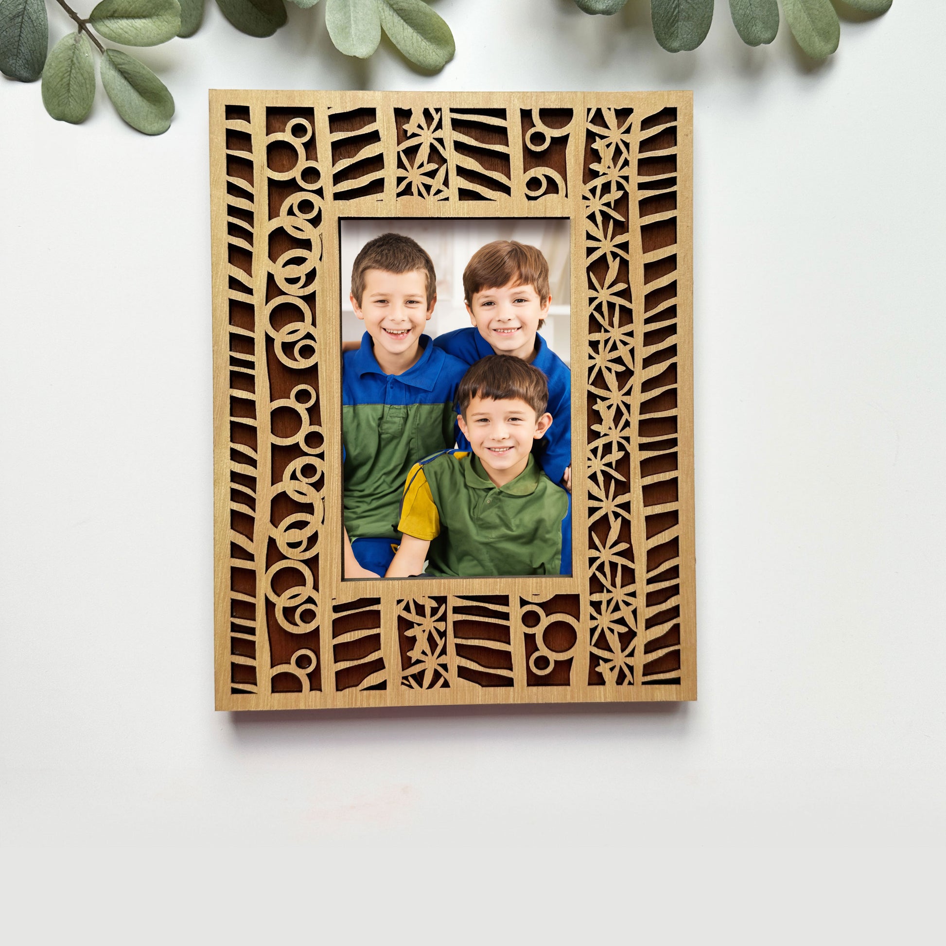 Wooden photo frame with decorative cutouts displaying a family photo on a light background.