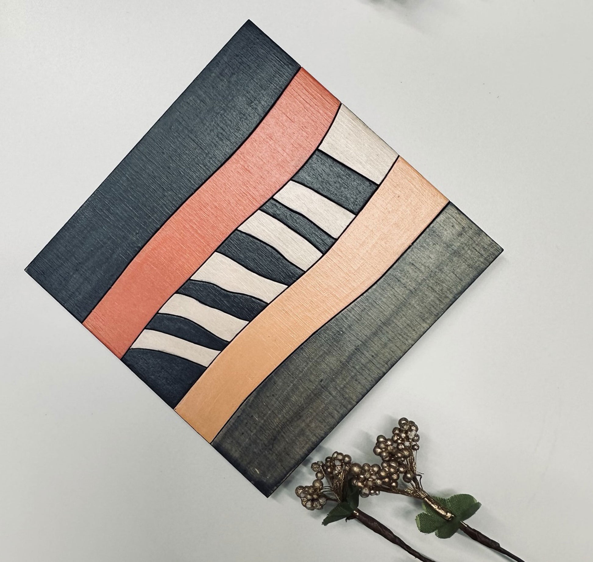 Rectangular painted coaster with geometric pattern on a plain background