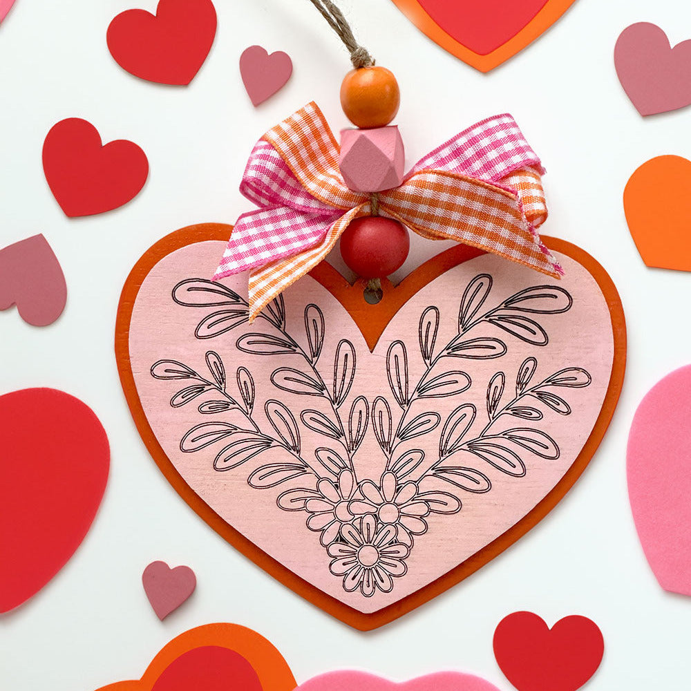 Decorative heart-shaped card with floral design and ribbon on a white background with scattered hearts.