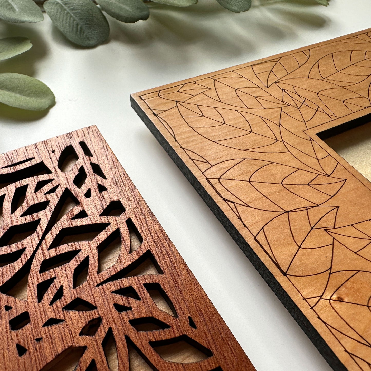 Two wooden laser-cut panels with leaf patterns on a light background