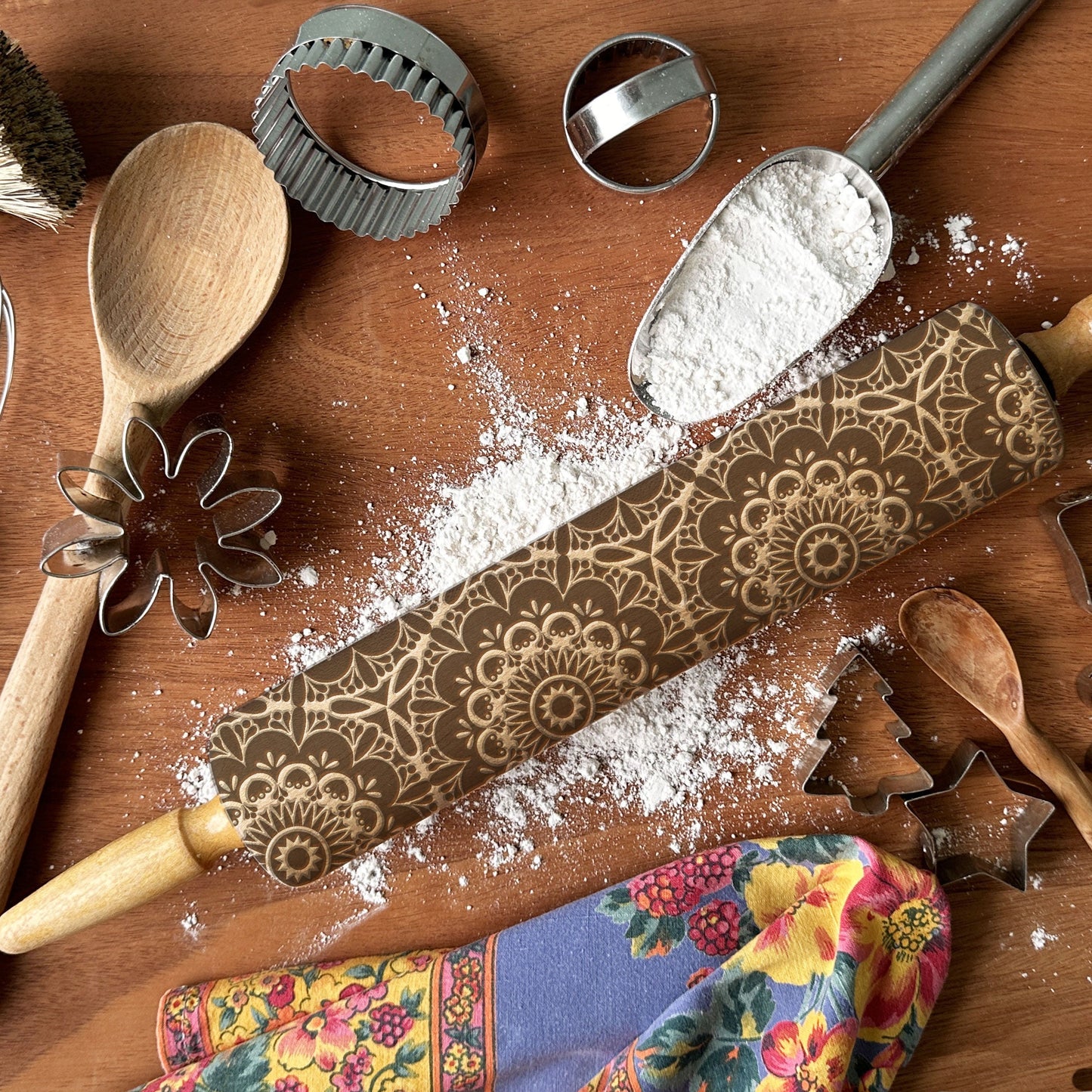 Decorative rolling pin with intricate patterns on a wooden surface with flour and baking tools.